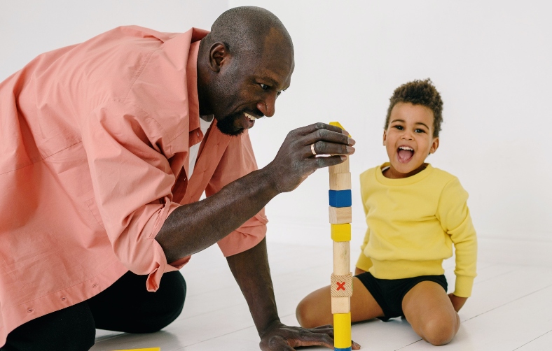 A father and his son play with wooden blocks together on the floor